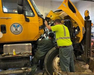 Two mechanics repairing a highway truck